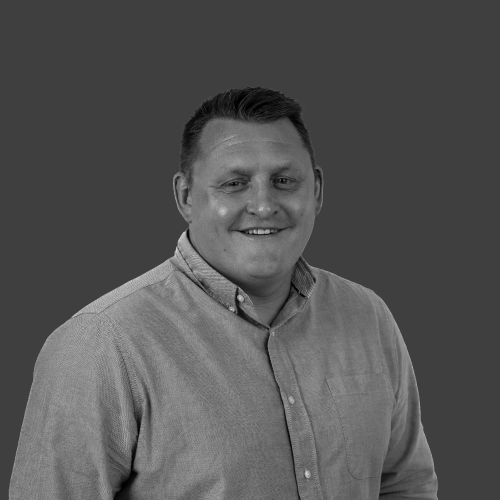 A man in a shirt is smiling in a black and white photo.