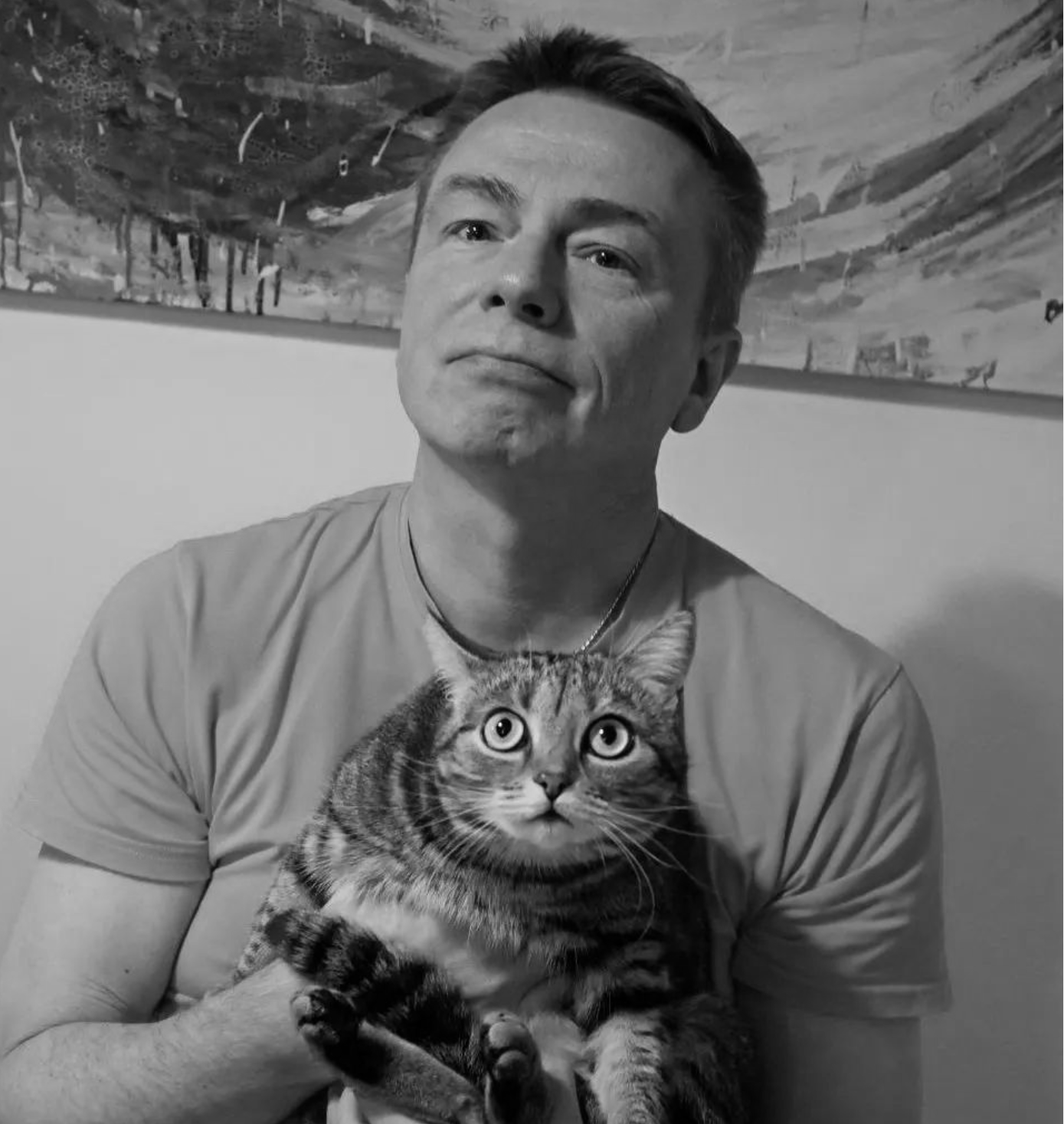 A man is holding a cat in his arms in a black and white photo