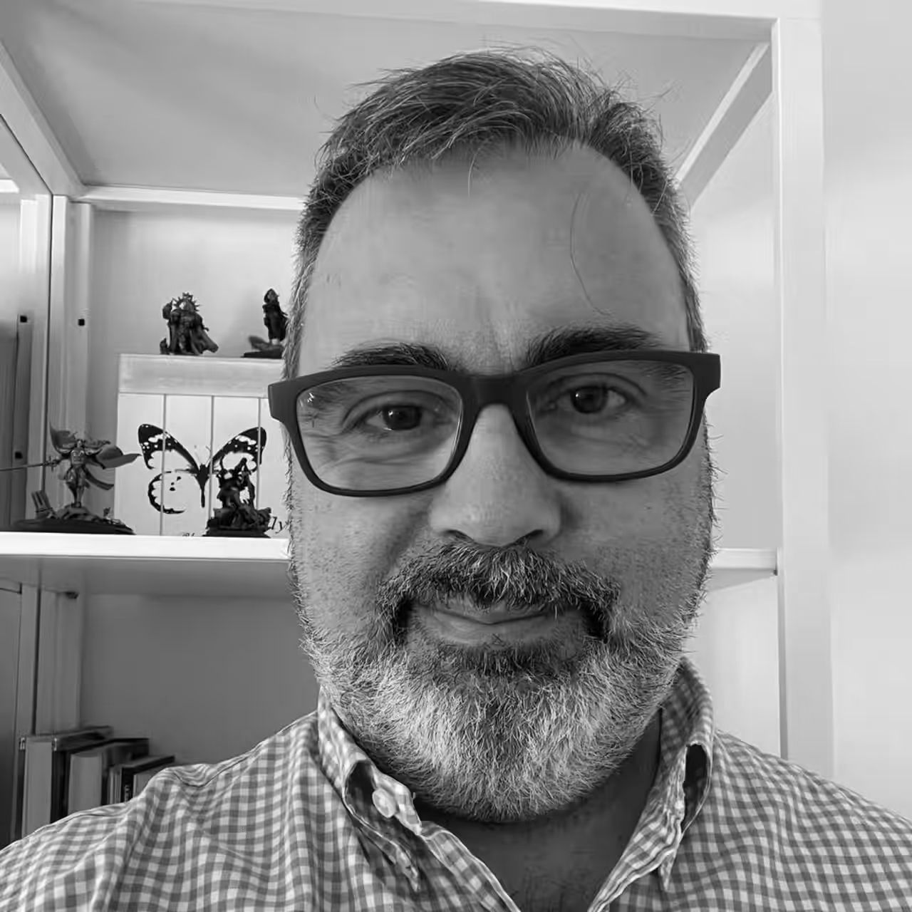 A man with a beard and glasses is smiling in a black and white photo.