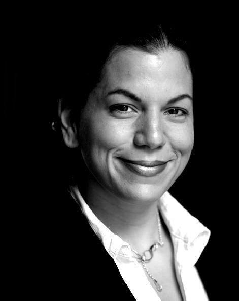 A woman with long hair and hoop earrings is smiling in a black and white photo.