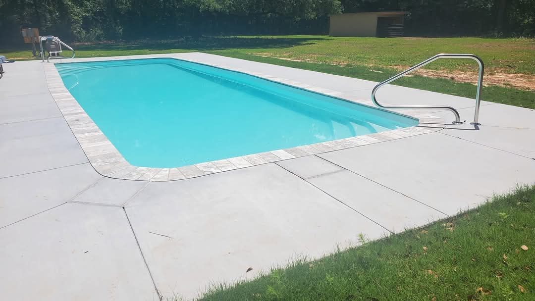 Rectangular swimming pool with light blue water and gray concrete deck.