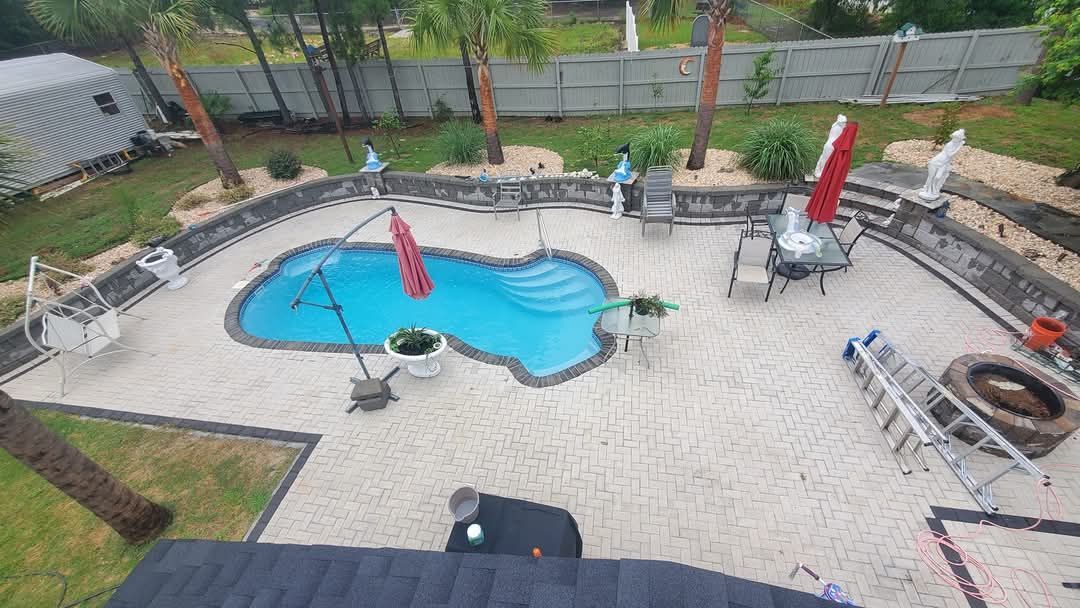 Backyard pool with patio, lounge chairs, and palm trees. Overcast sky.