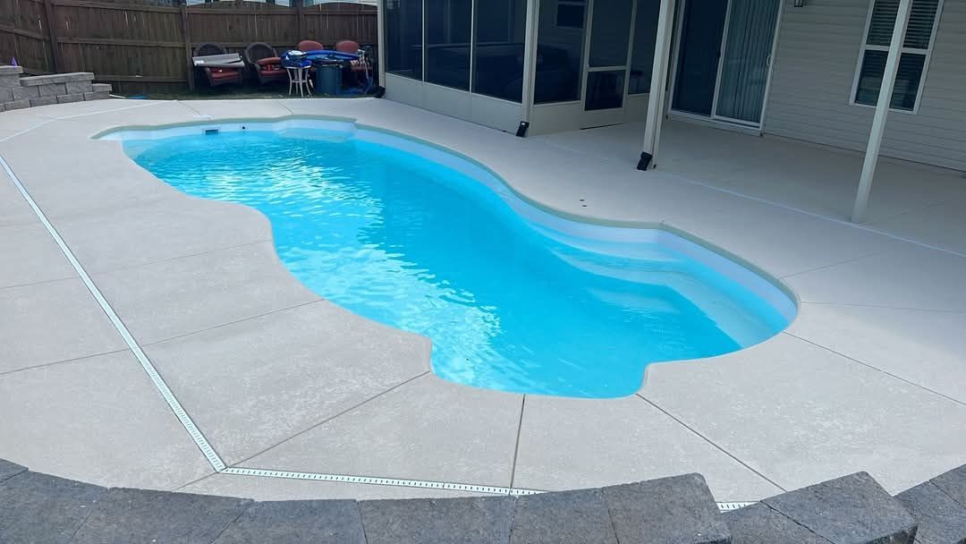 A blue swimming pool surrounded by a concrete patio.