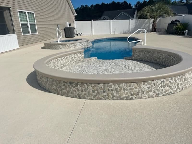 Swimming pool with tiled walls and a surrounding concrete patio.