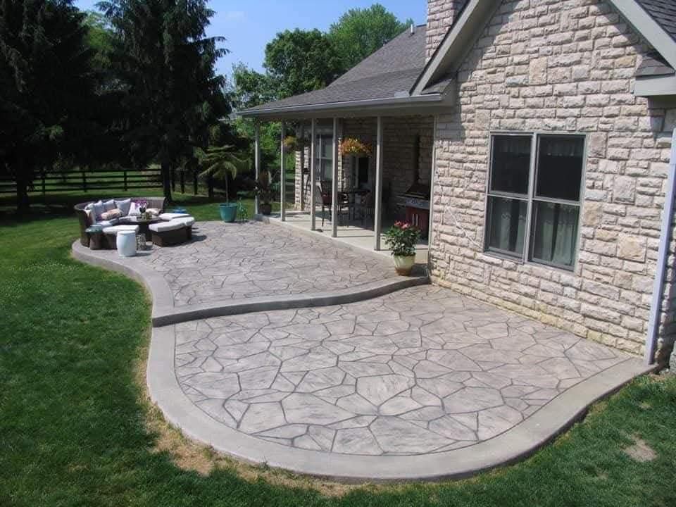 Concrete patio with stone-patterned surface; grass and house in background.