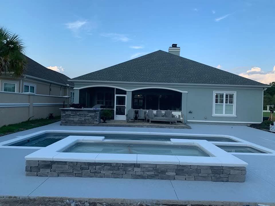 Backyard with pool, patio, and house. Light blue exterior, stone accents, gray concrete deck, and screened-in porch.