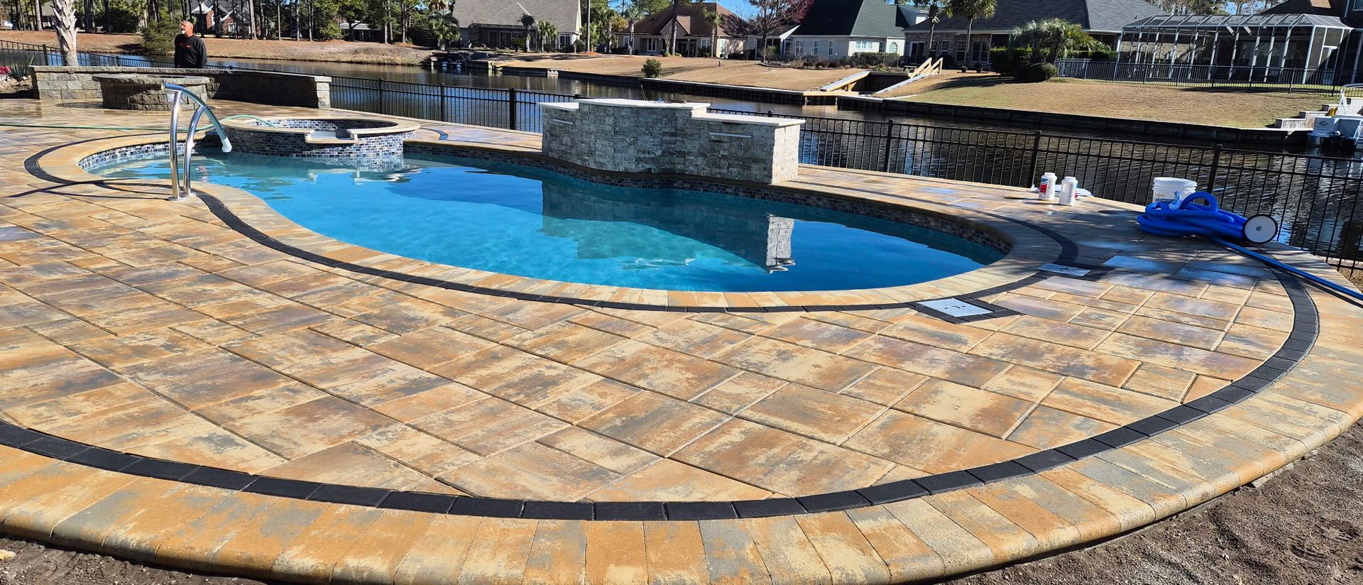 A swimming pool with stone pavers and a water feature.