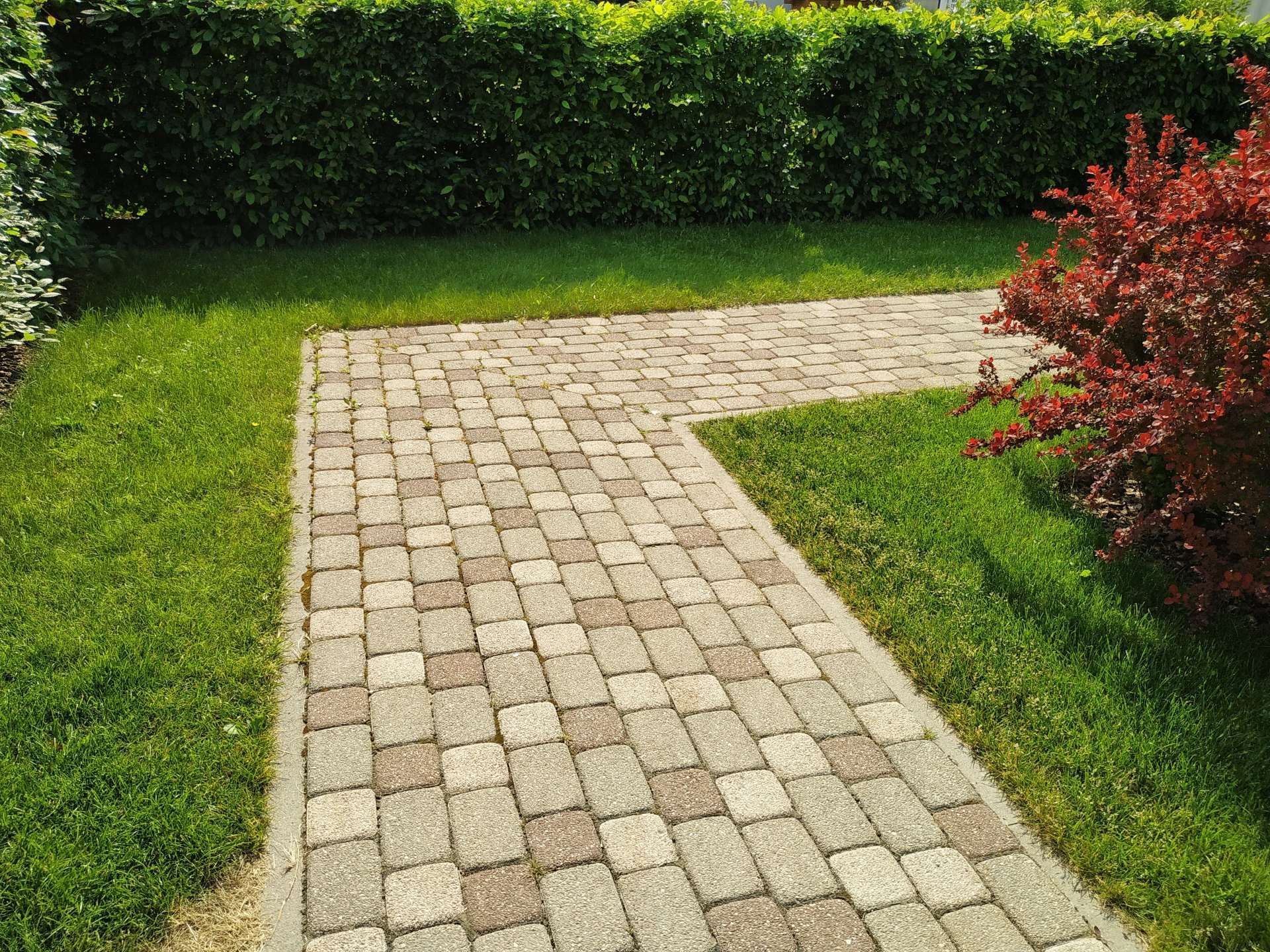 Woman in straw hat smiles, holding wine glass near a lake.