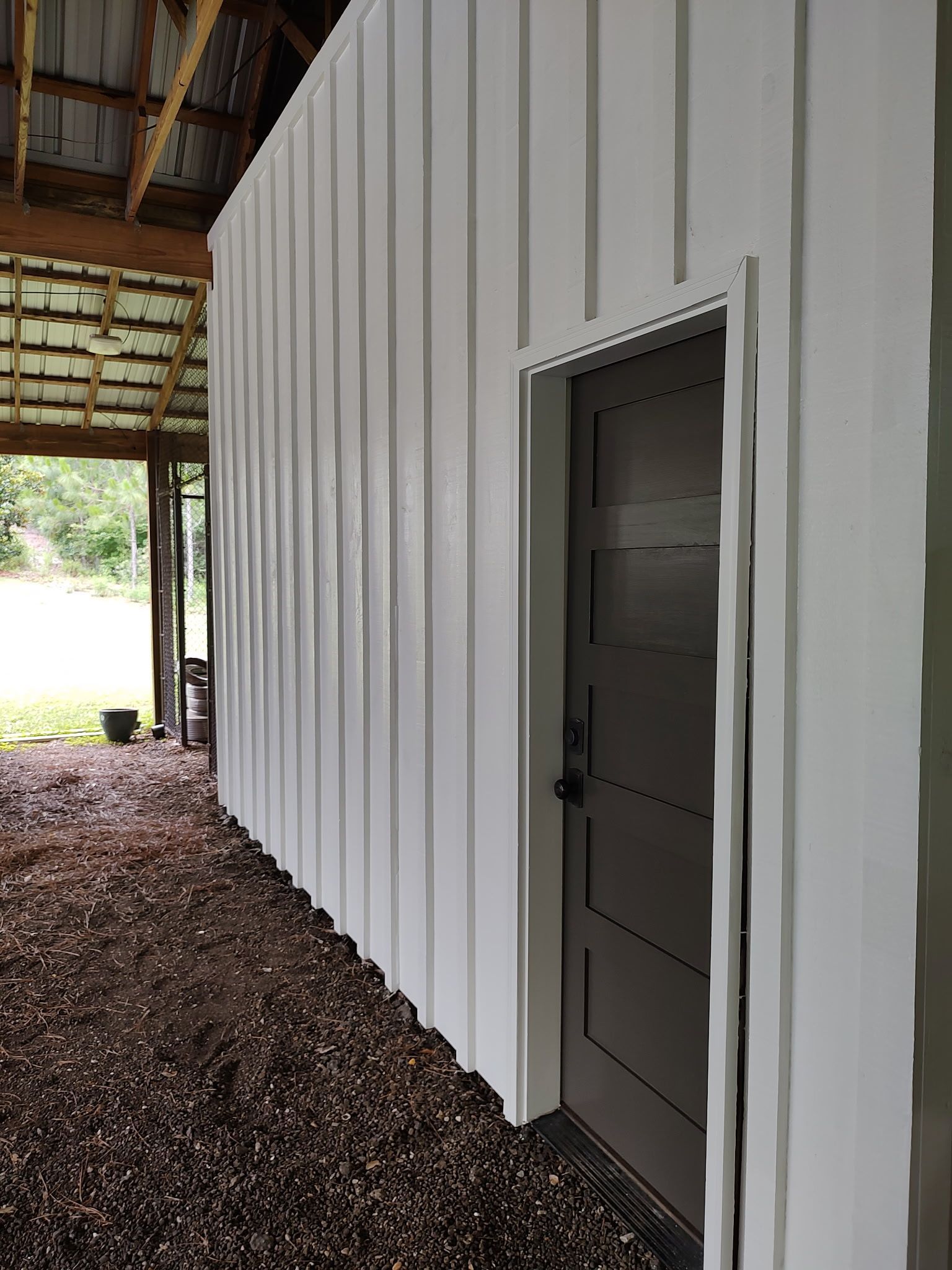 White corrugated metal wall with gray door in a barn.