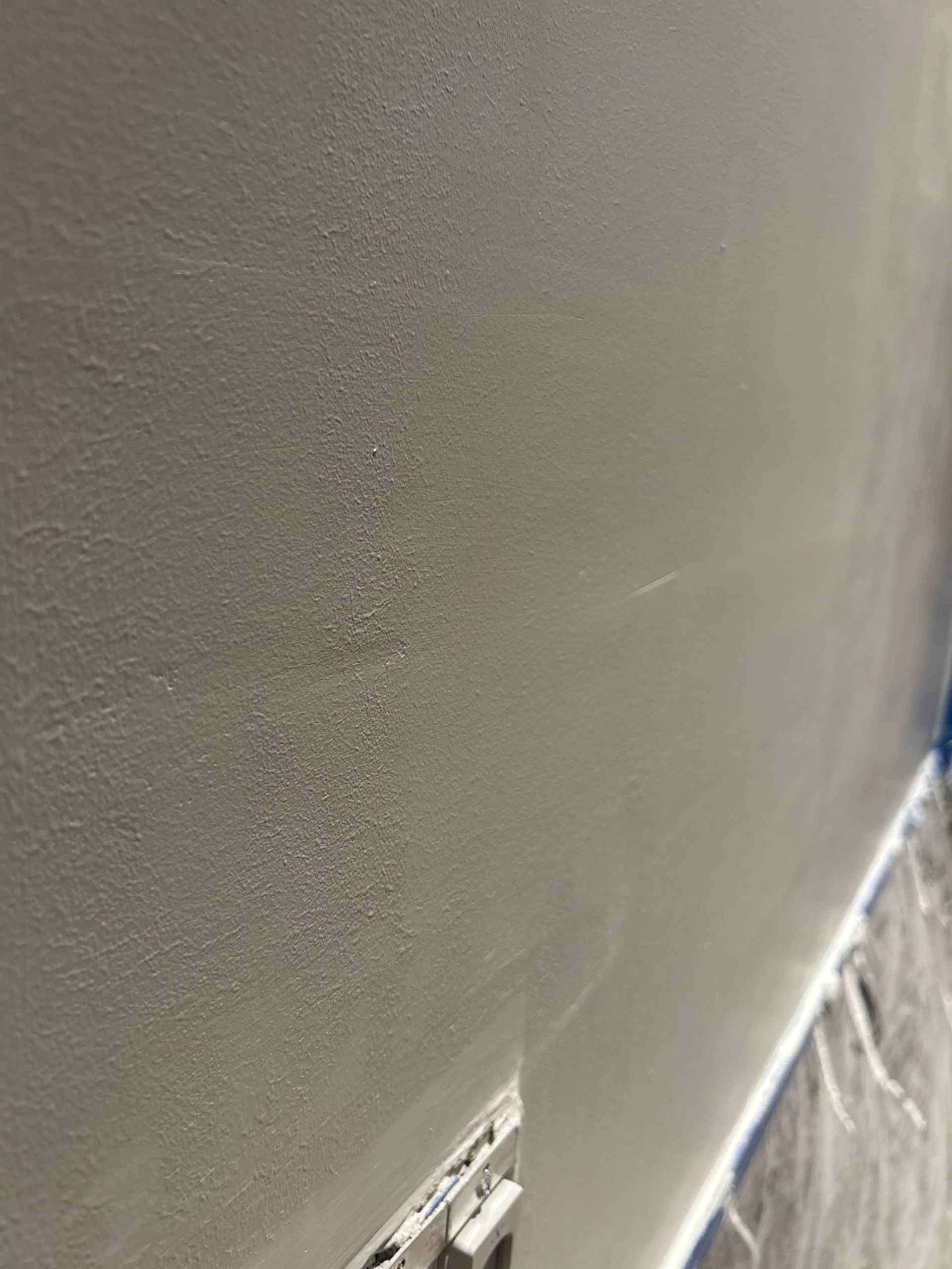Close-up of a gray painted wall, with some visible texture and a light switch.