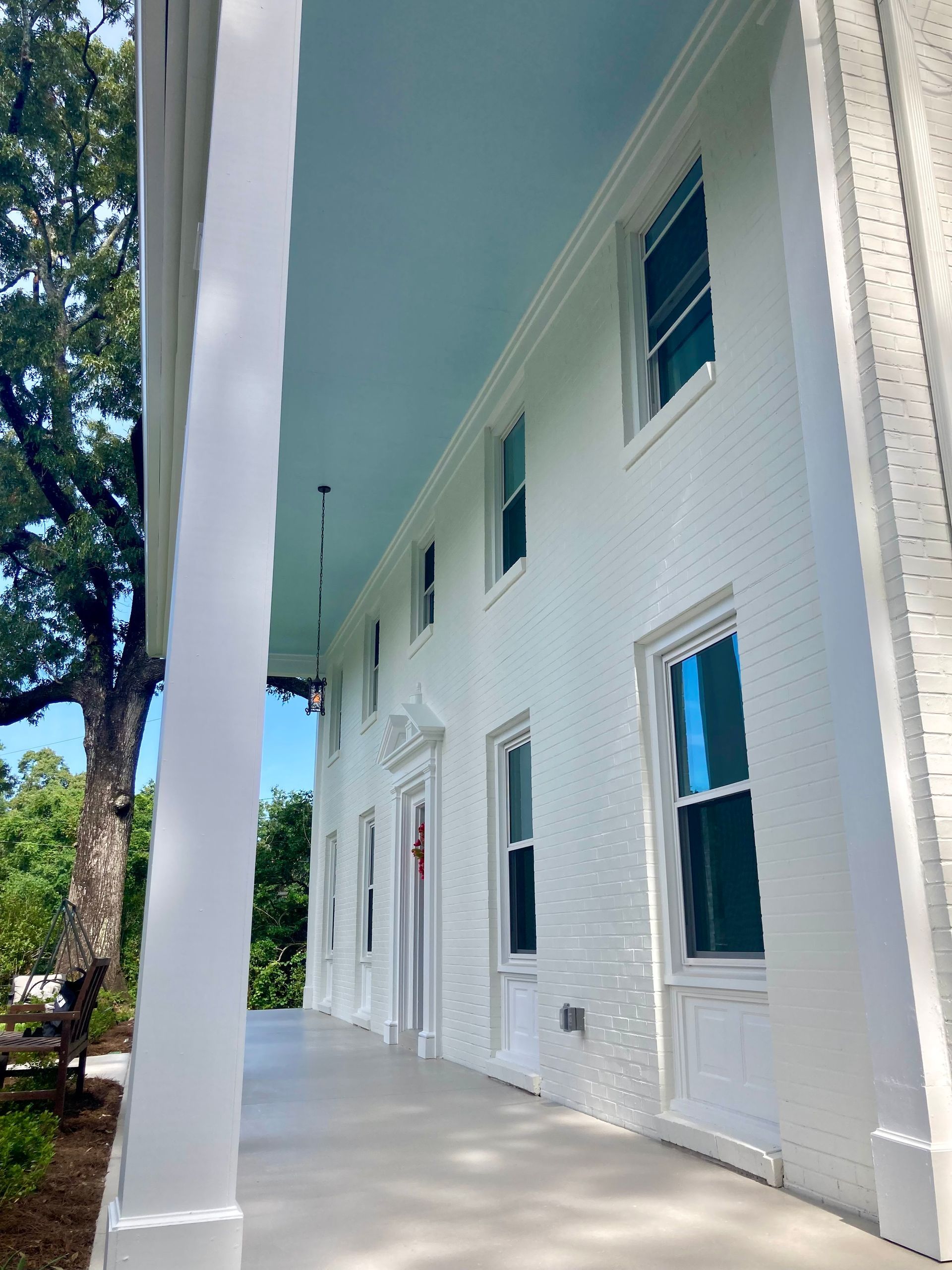 White building with columns, light blue ceiling, several windows. Outdoors, sunny.