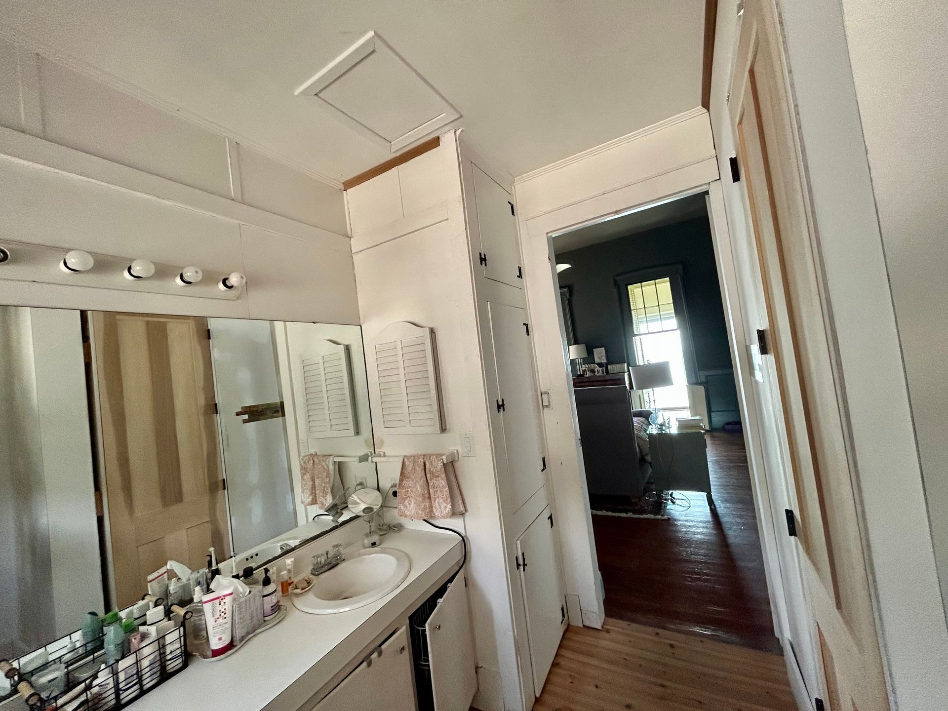 Bathroom interior with a sink, mirror, and an open door to another room.