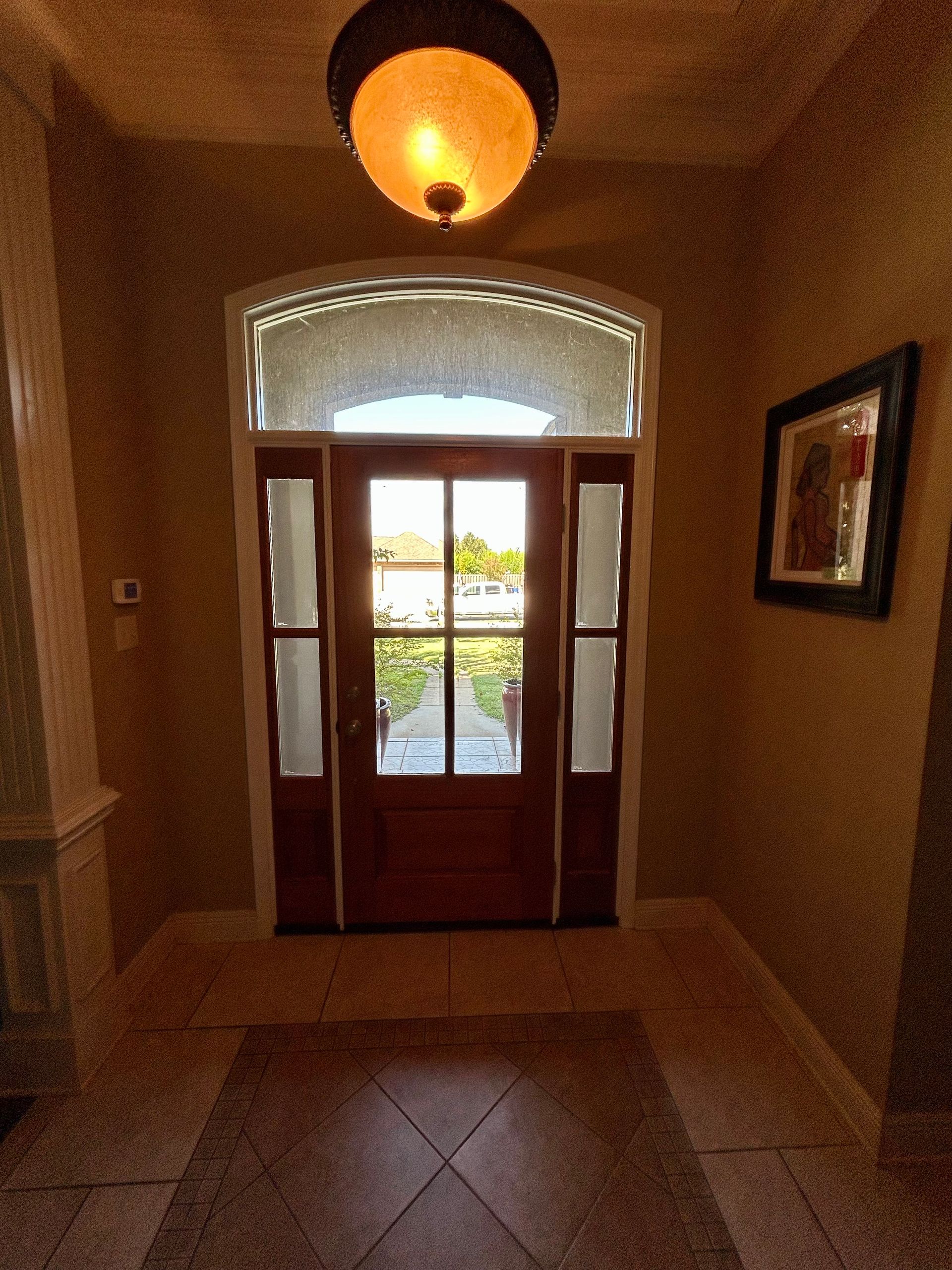 Interior entryway with a wooden door, sidelights, and a hanging light fixture.