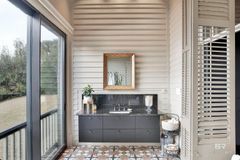 Bathroom with dark gray vanity, decorative mirror, and patterned floor. A large window overlooks greenery.