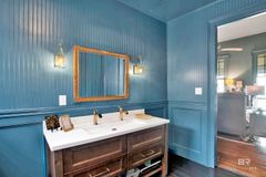 Blue bathroom with gold-framed mirror, marble countertop, and dark wooden vanity.