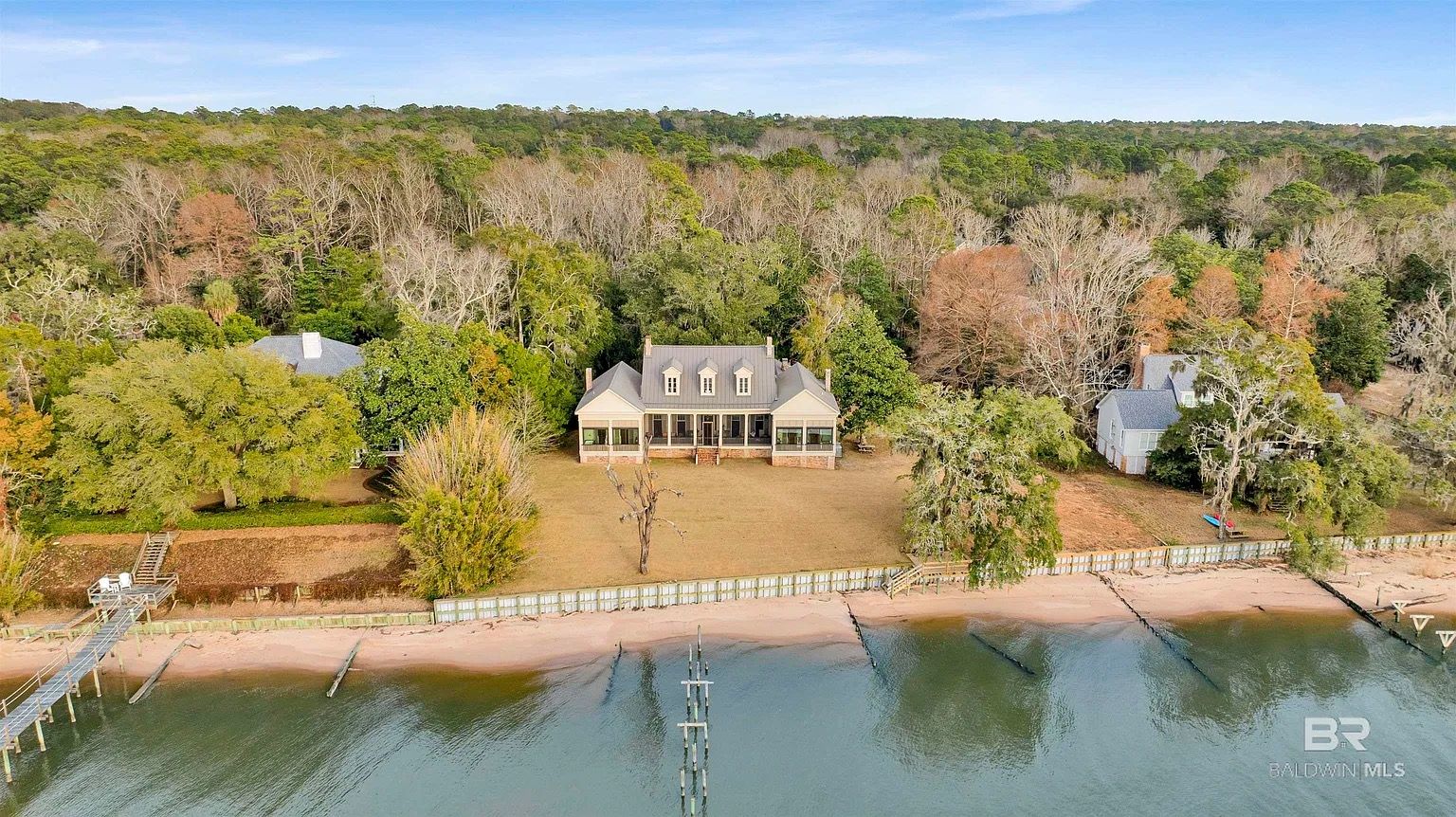 House with a porch on a waterfront surrounded by trees.