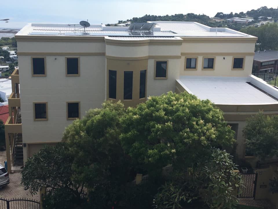 A large white building with a white roof is surrounded by trees — Marteene Painting Services In Kirwan, QLD