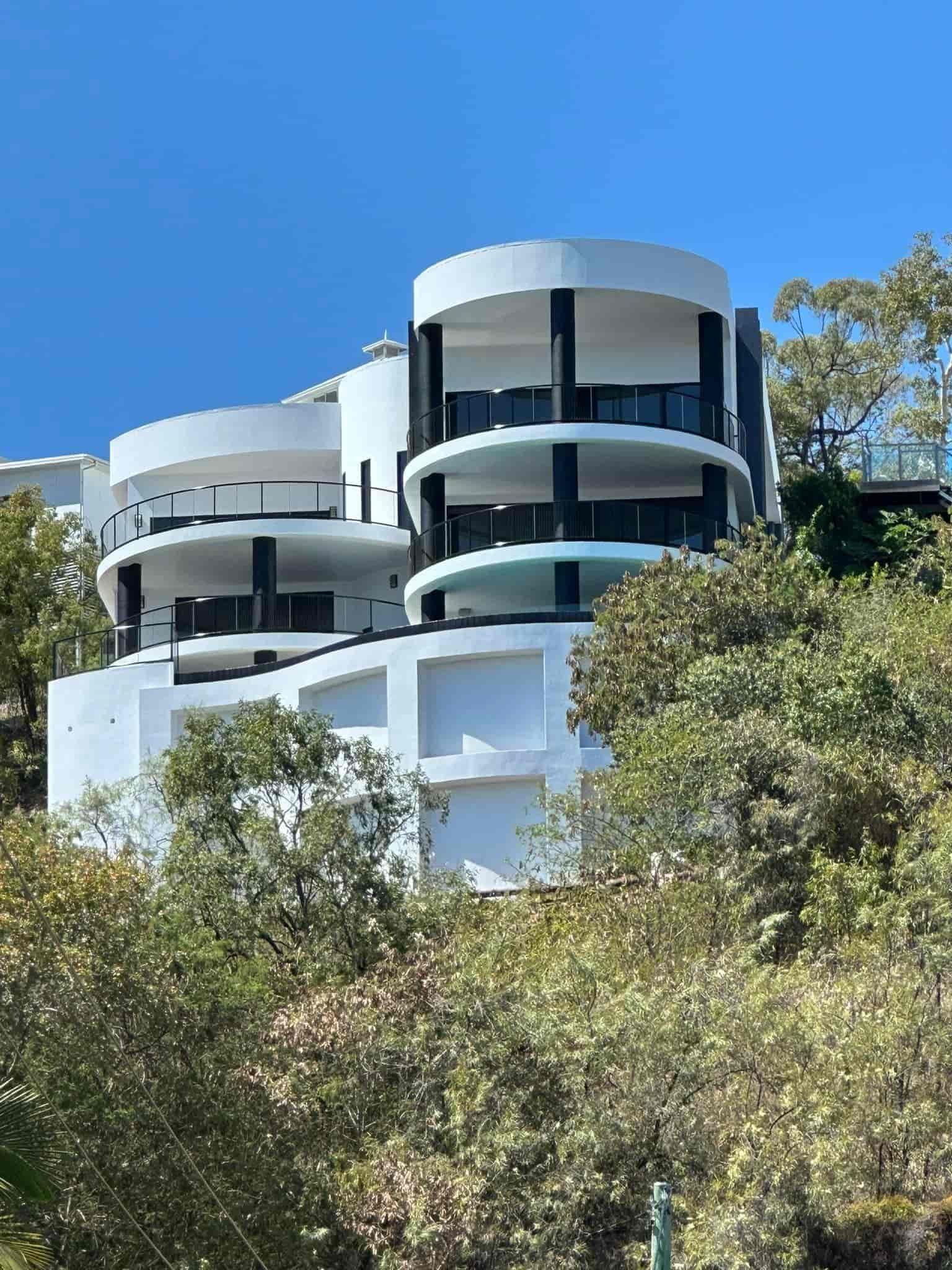 A large white house is sitting on top of a hill surrounded by trees — Marteene Painting Services In Kirwan, QLD.