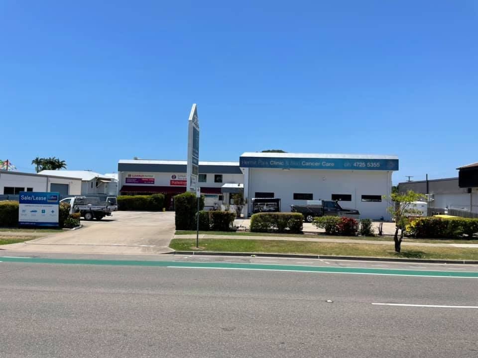 A large white building is sitting on the side of a road.