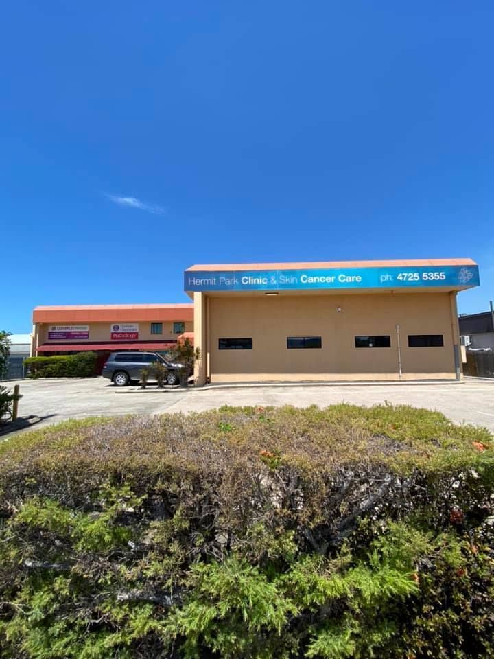 A building with cars parked in front of it and a blue sky in the background.