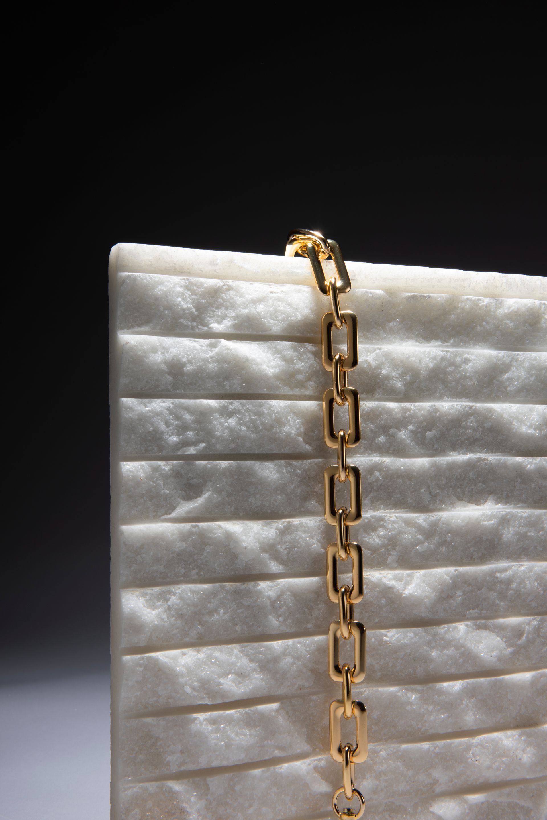 A white clutch bag with a gold chain hanging from it.