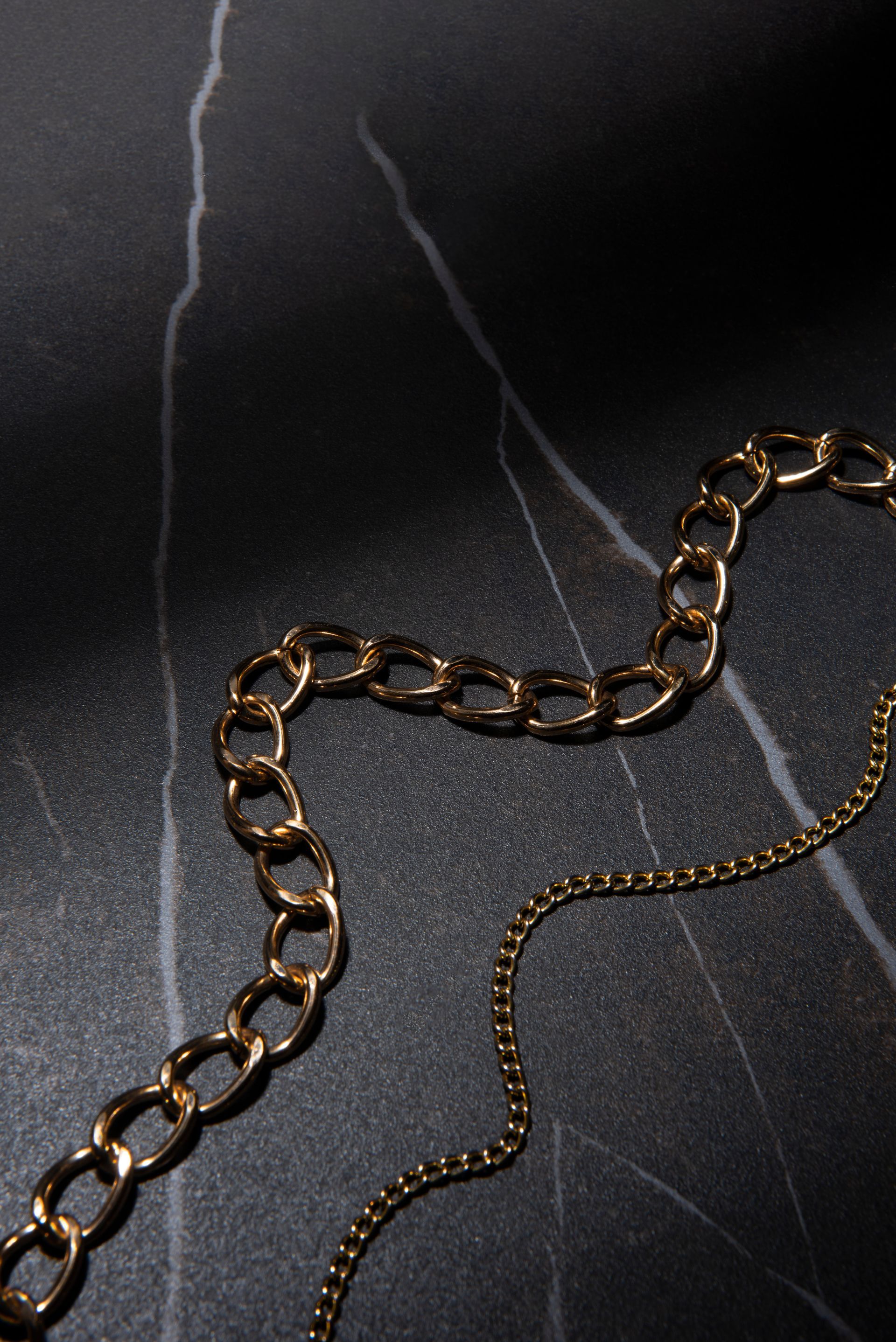 A close up of a gold chain on a black surface.