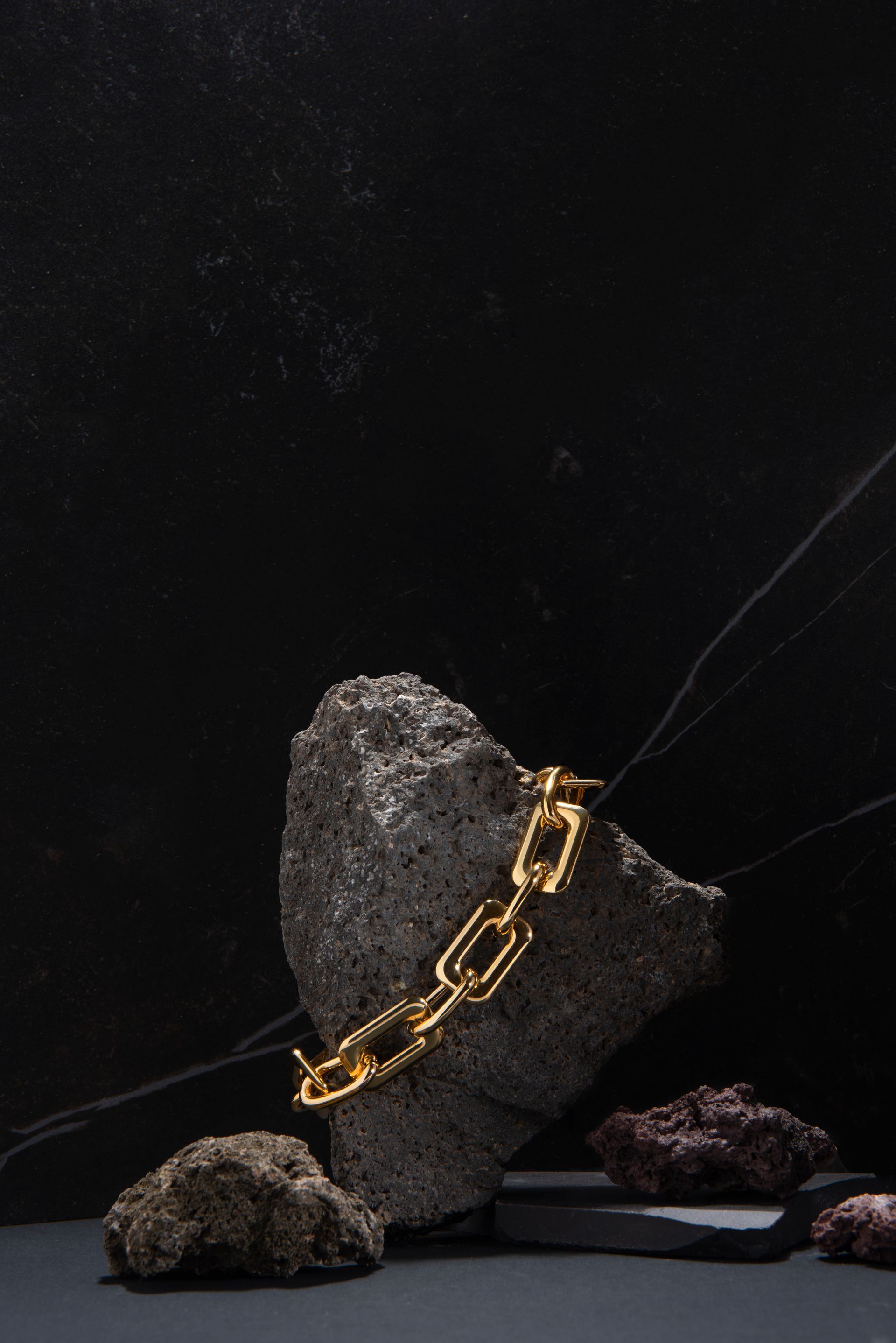 A gold chain is sitting on top of a rock.