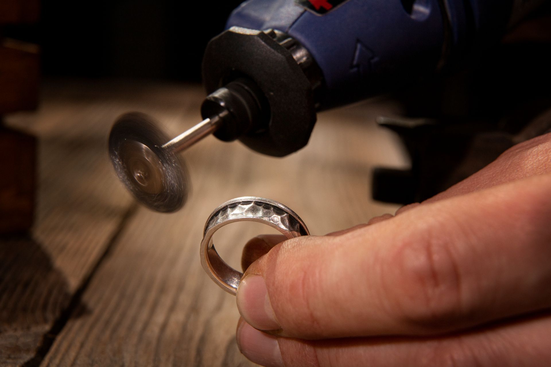 A person is polishing a silver ring with a machine.