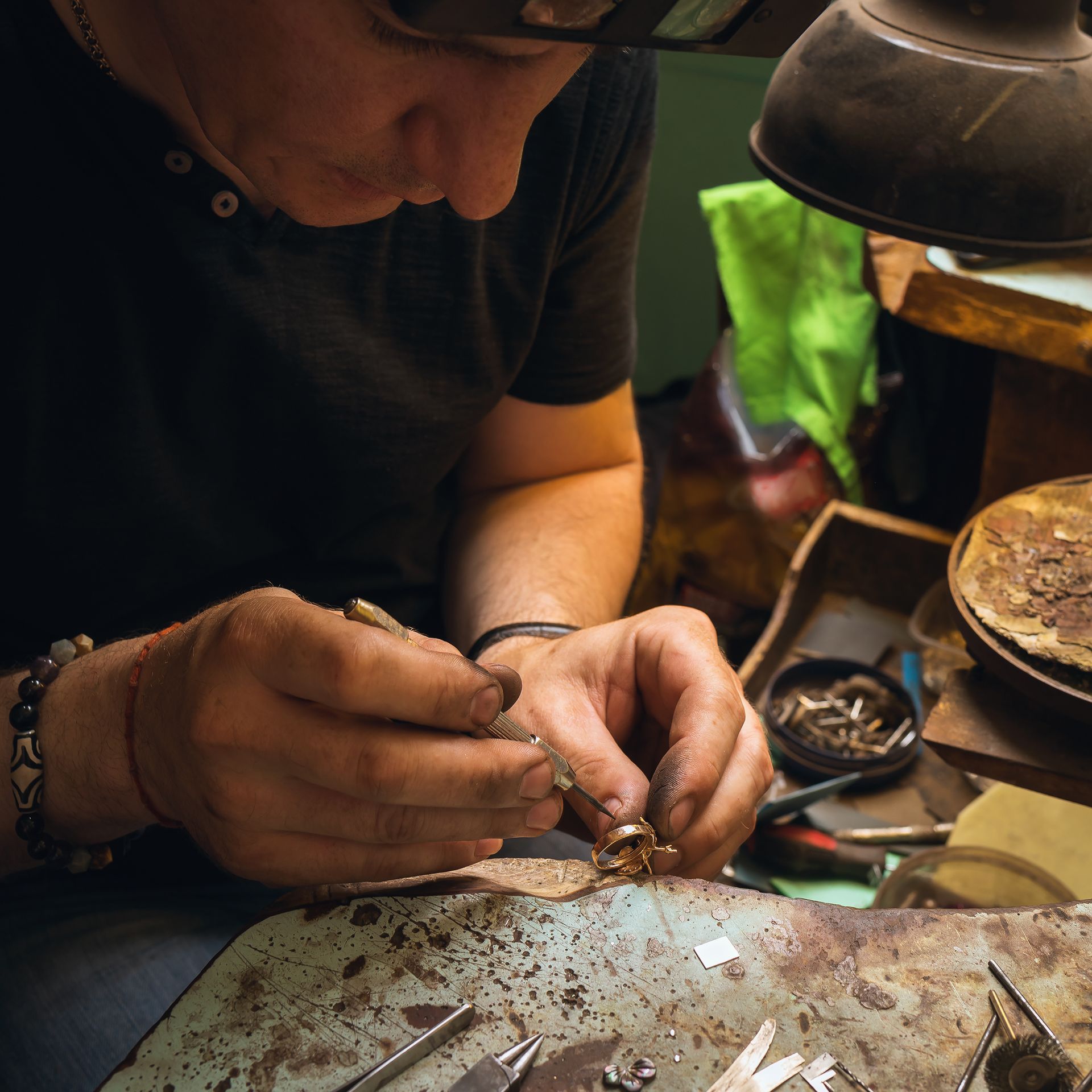 A man is working on a piece of jewelry on a table