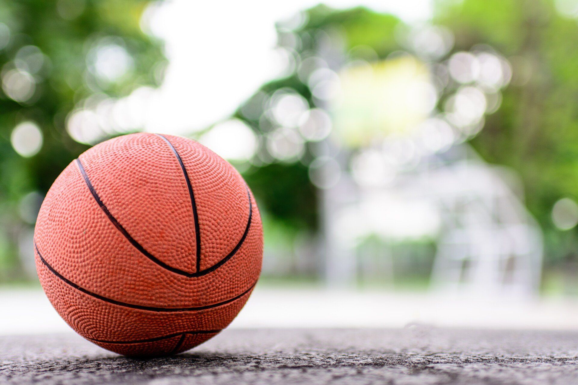 Basketball on a gray surface, with a blurry green background.