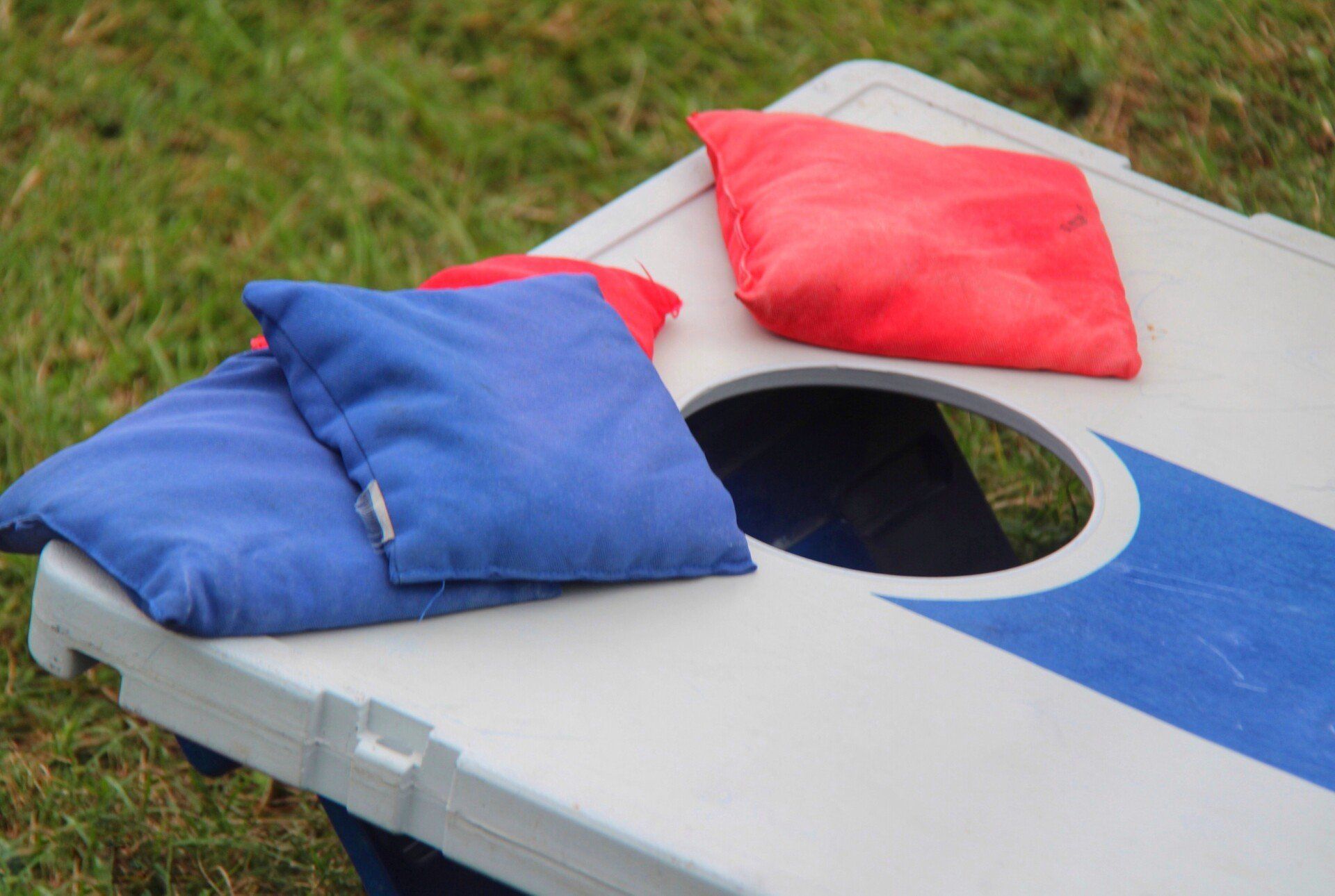 Cornhole board with blue and red bean bags.