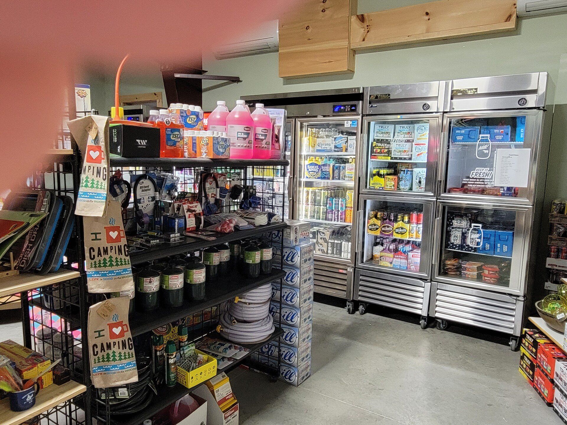 Interior of a store displays shelves with merchandise and refrigerated beverage coolers.