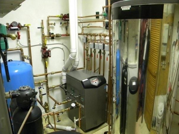 Technician performing maintenance on a heating boiler, inspecting and servicing its components for optimal functionality.