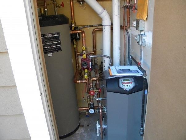 Plumber sets up electric heating boiler at home bathroom.