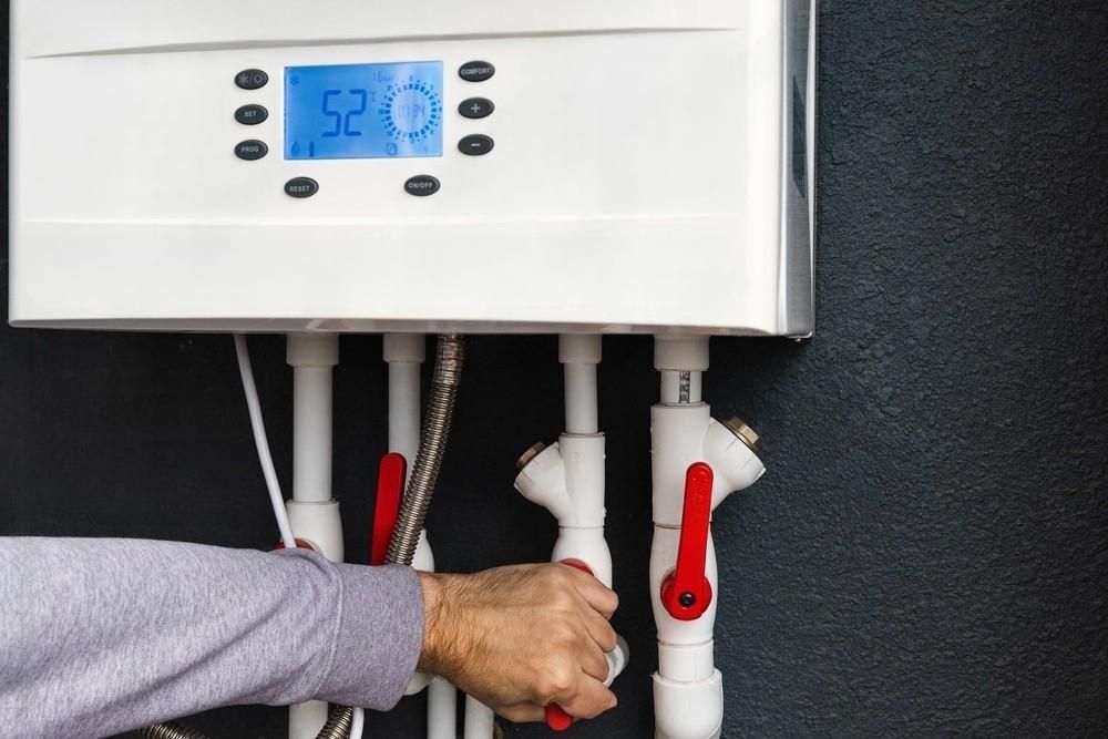 Plumber sets up electric heating boiler at home bathroom.