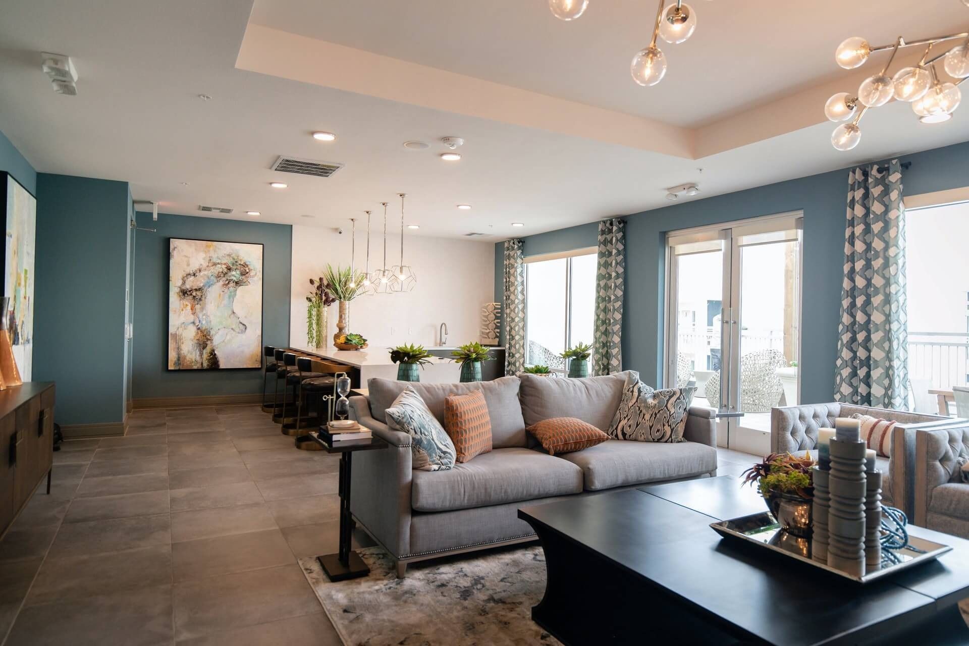 Bright modern living room with gray sofa, coffee table, tall windows, and blue accent walls