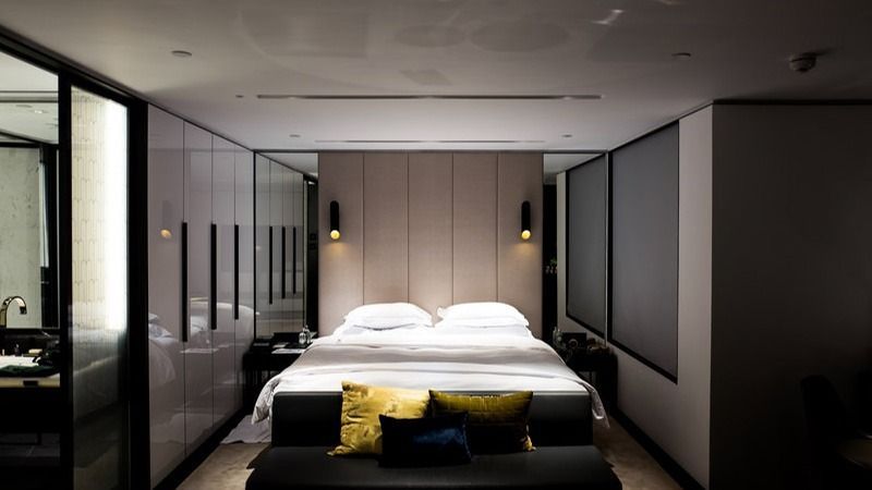 Modern minimalist bedroom with a bed, black-framed glass walls, and soft pendant lighting