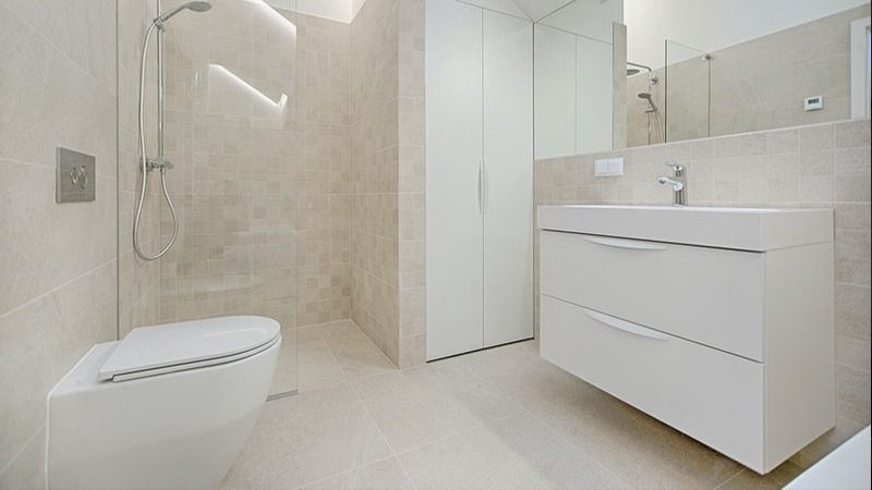 Modern white bathroom with walk-in shower, wall-mounted toilet, and vanity sink