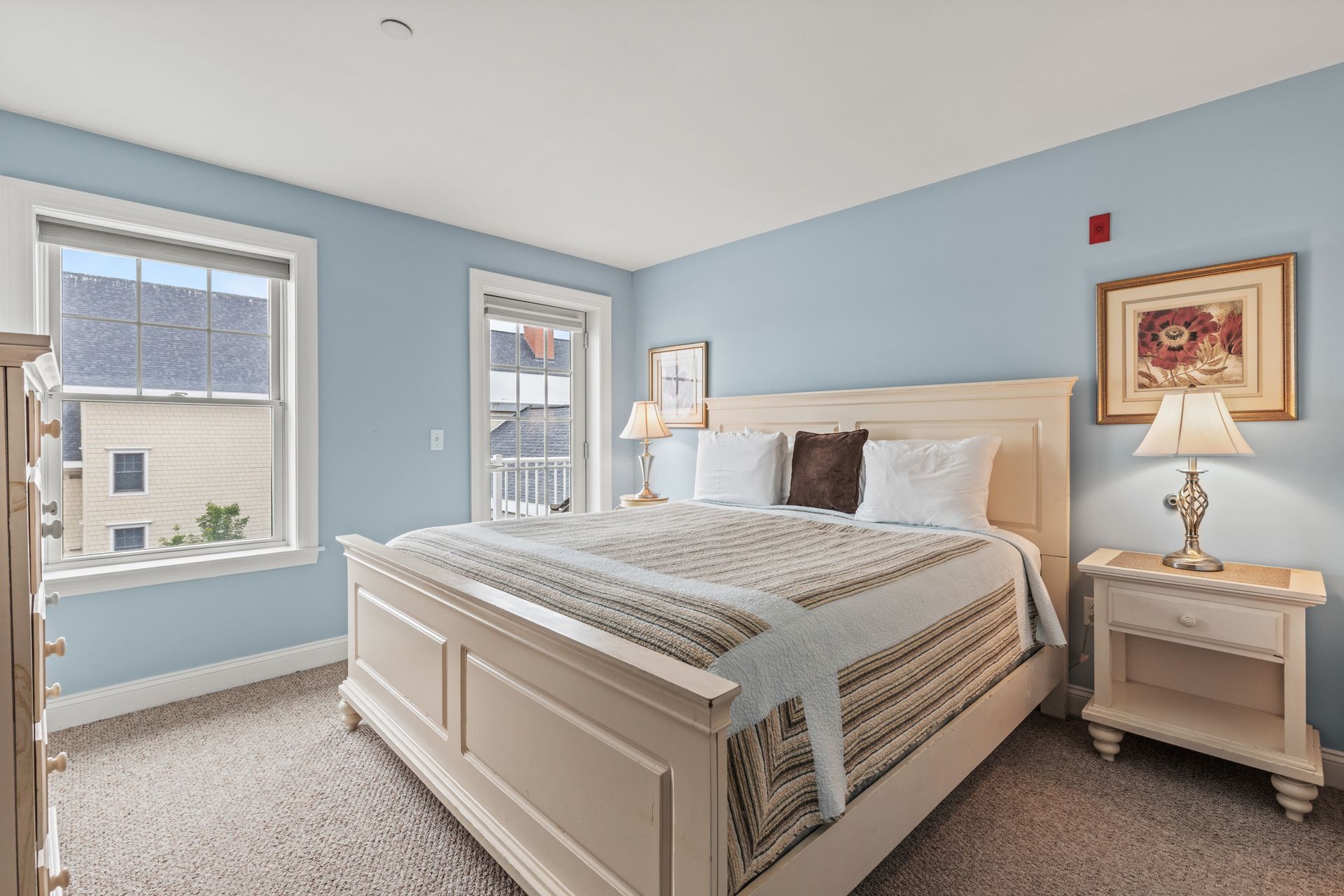 A bedroom with a king size bed , nightstand , dresser and two windows.