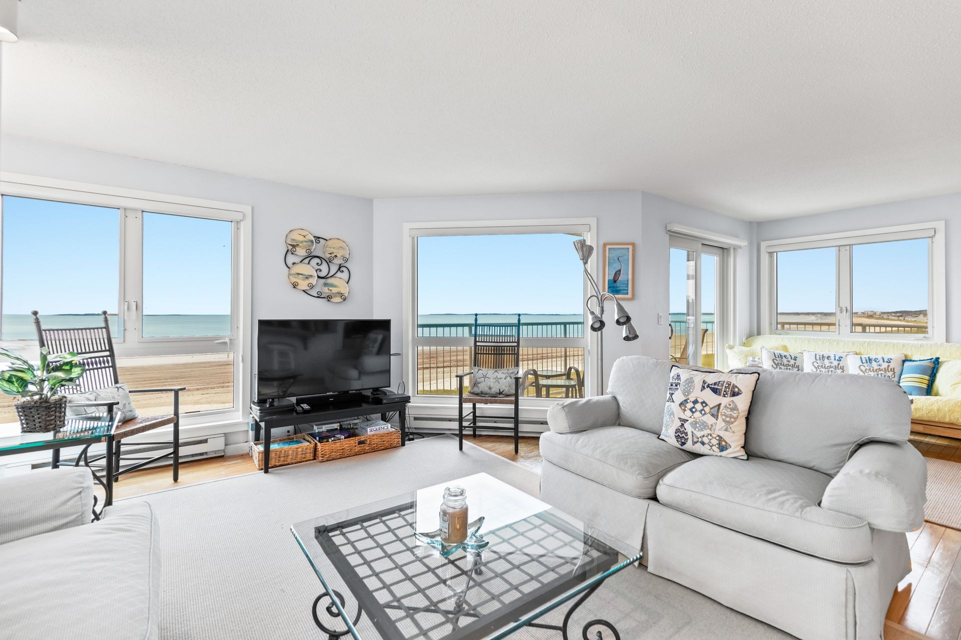 A living room with a couch , table , television and a view of the ocean.
