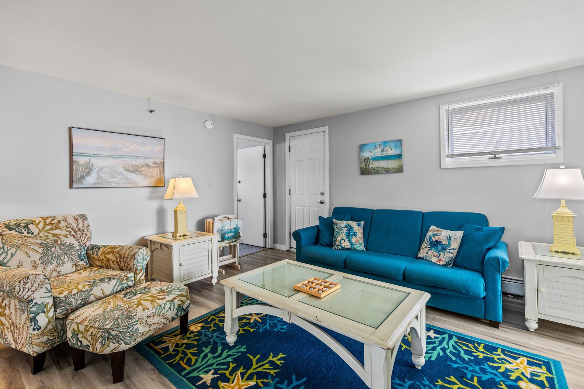 A living room with a blue couch , chair , coffee table and rug.