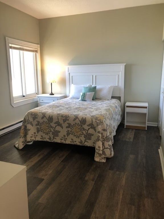 A bedroom with a bed , two nightstands , and a window.