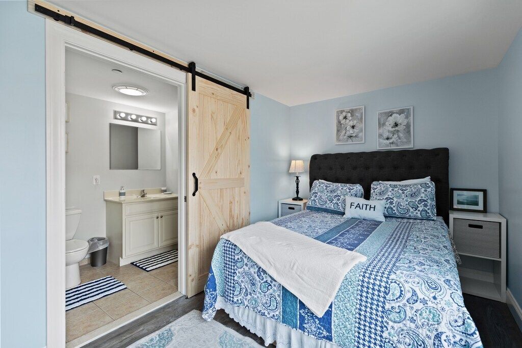 A bedroom with a king size bed and a sliding barn door leading to a bathroom.