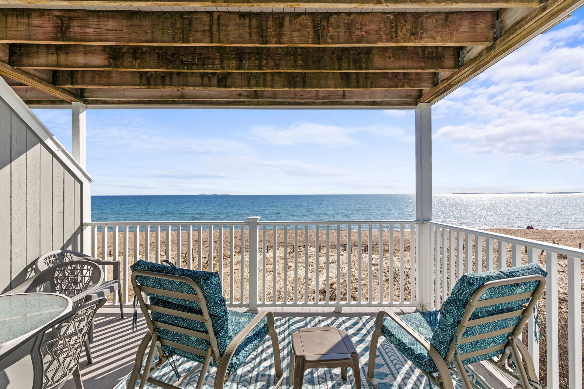 A balcony with chairs and a table overlooking the ocean.