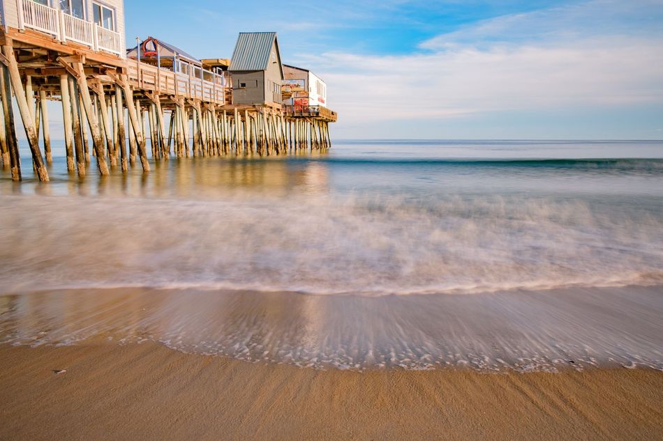 A pier on a beach with waves crashing against it