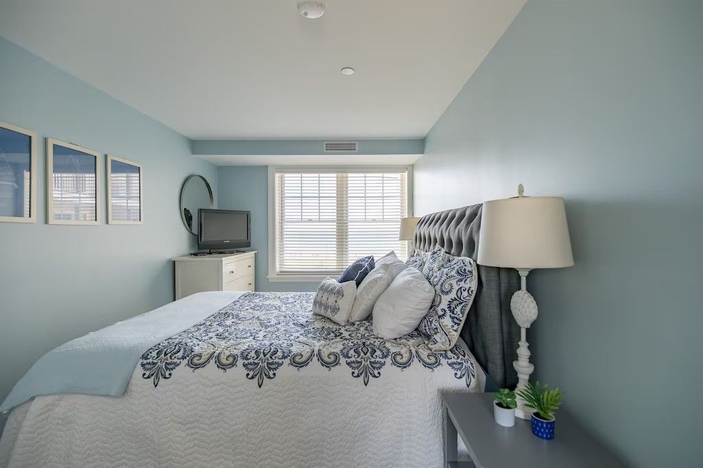 A bedroom with a king size bed , nightstand , lamp and television.