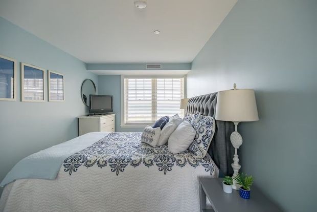 A bedroom with a king size bed , nightstand , lamp and television.