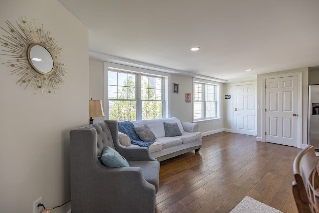A living room with a couch , chair and a mirror on the wall.