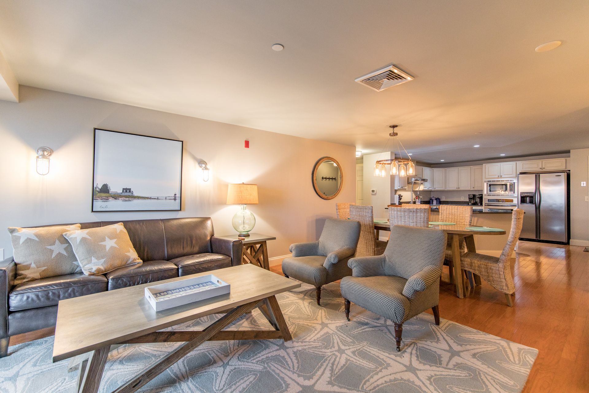 A living room with a couch , chairs , a coffee table and a dining table.