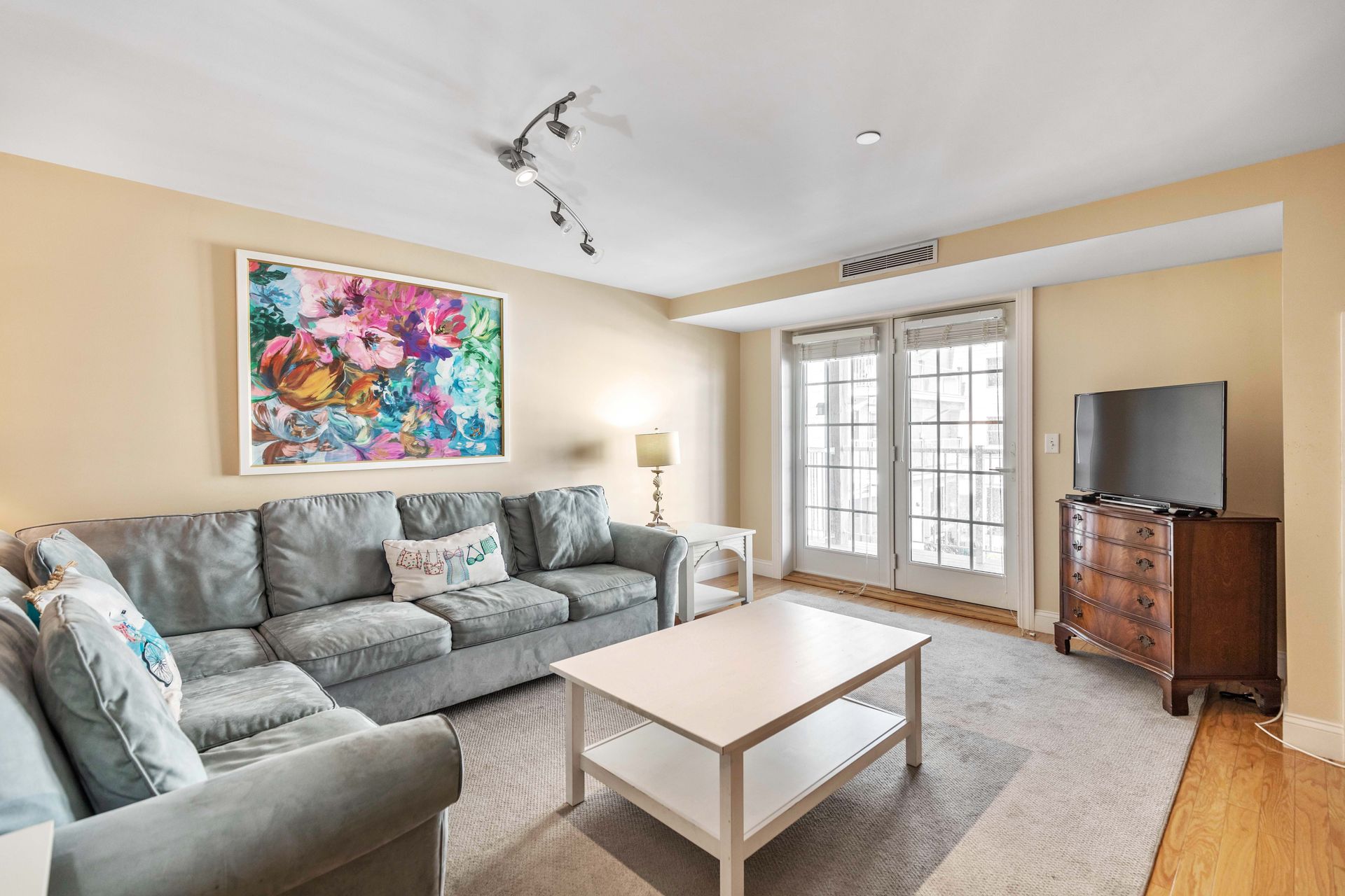 A living room with a couch , coffee table , television and a painting on the wall.
